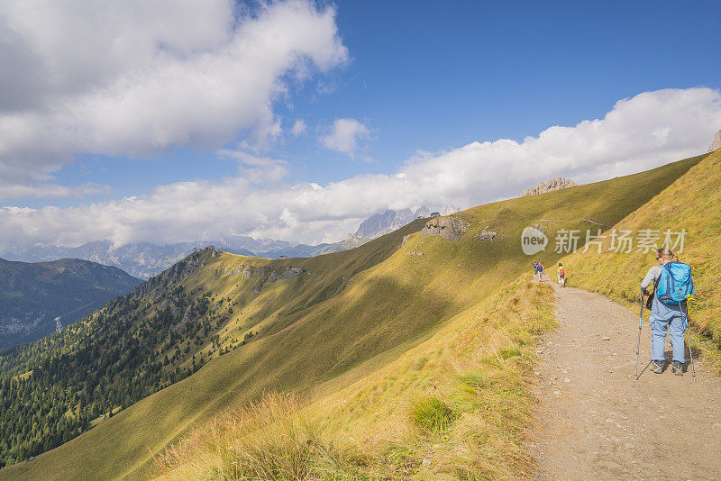 在意大利北部多洛米特，一位年长的女士和一些游客在Viel dei Pan的陡峭斜坡上徒步旅行，从Fedaia山口到Pordoi山口。
